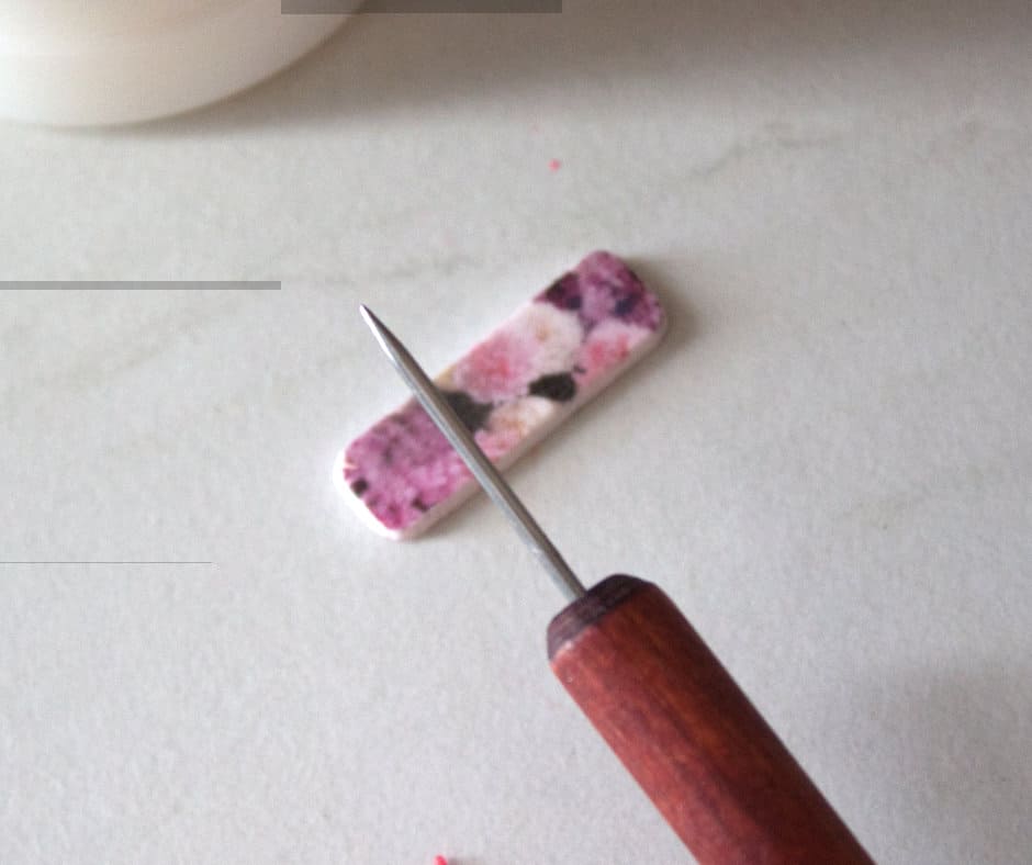 The image features a pair of beautiful polymer clay earrings that have been given a shiny finish. In the foreground, there is a small bottle of glossy varnish and a paintbrush. The artist has applied a thin layer of the varnish onto the earrings, covering every nook and cranny to ensure an even coat. As the varnish dries, it creates a smooth and reflective surface that brings out the colors and details of the earrings. This image perfectly captures the simple yet effective technique of using glossy varnish to give polymer clay jewelry a professional-looking shine.