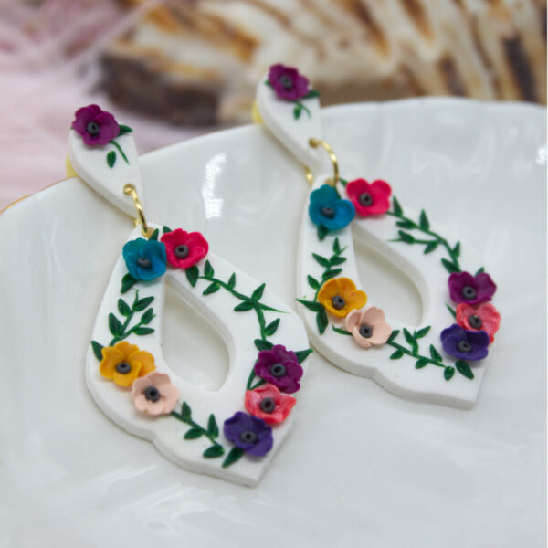 Introducing our beautifully handcrafted Polymer Clay Earrings, designed to add a touch of elegance and color to any outfit. These unique earrings feature a stunning white base, intricately adorned with vibrant, multi-colored flowers that will surely make you stand out from the crowd.