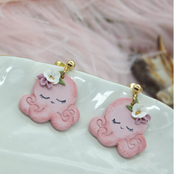 Adorable pink octopus-shaped summer earrings made from polymer clay, featuring a white flower accent for a charming beach-inspired look