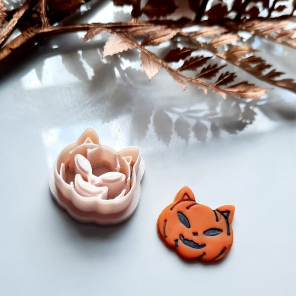 A cat pumpkin polymer clay cutter on a wooden table, perfect for creating Halloween-themed polymer clay earrings