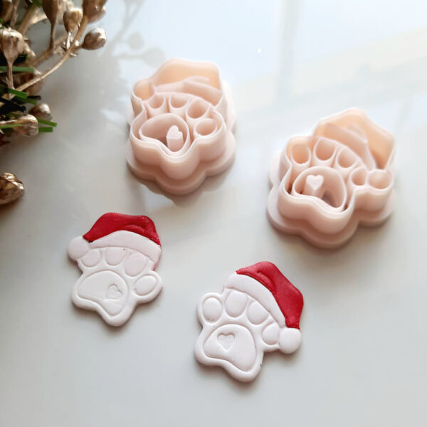 Polymer clay cutter designed in the shape of a paw print with a festive Christmas hat.