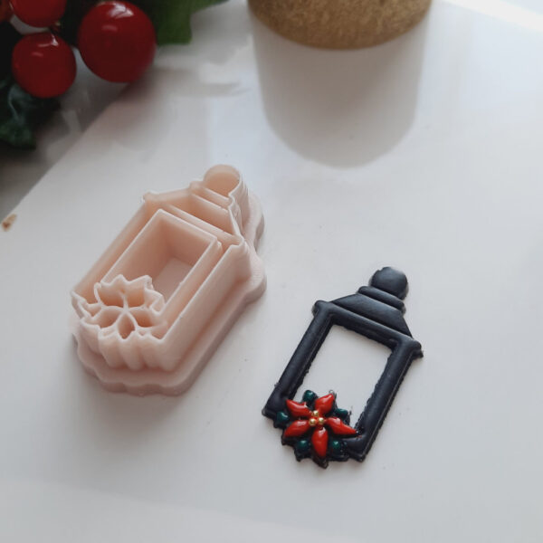 A polymer clay cutter shaped like a lantern and poinsettia, perfect for crafting Christmas-themed polymer clay creations