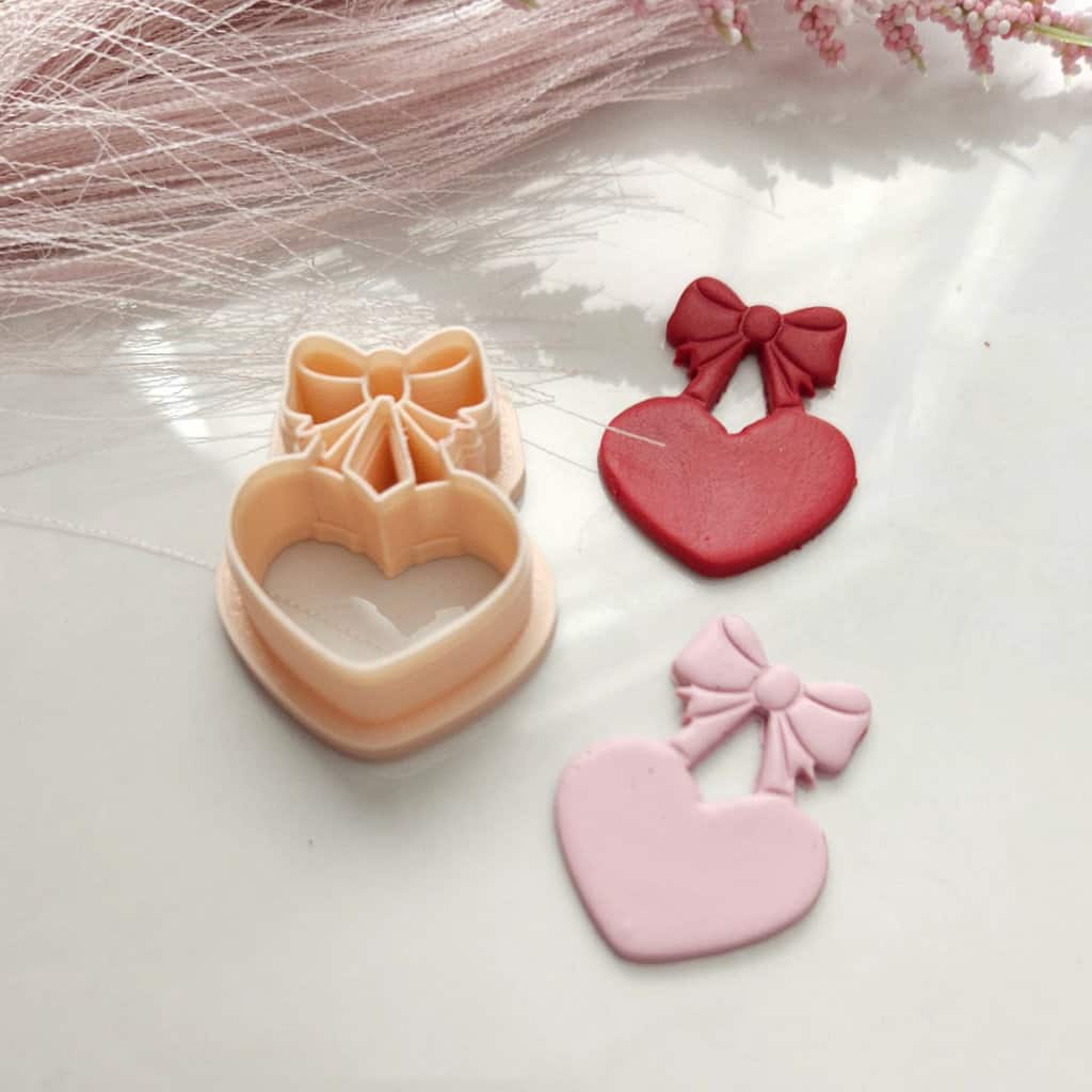 Heart-shaped Valentine's Day polymer clay cutter with bow detail for crafting festive earrings.