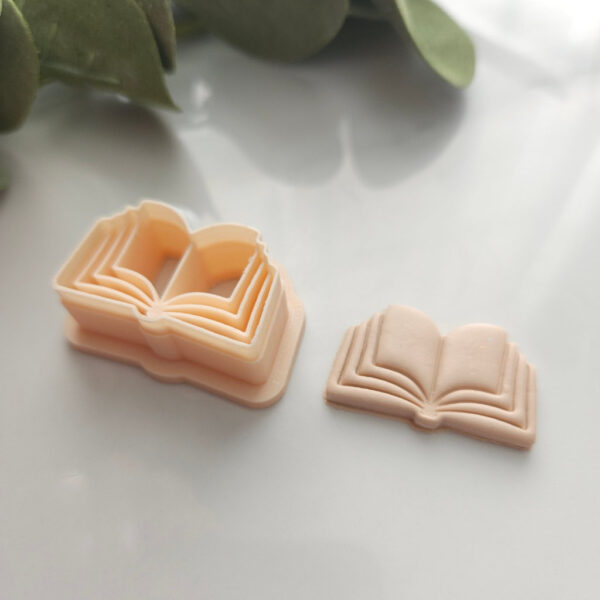 Book Shaped Clay Cutter next to a polymer clay earring sample with leafy background