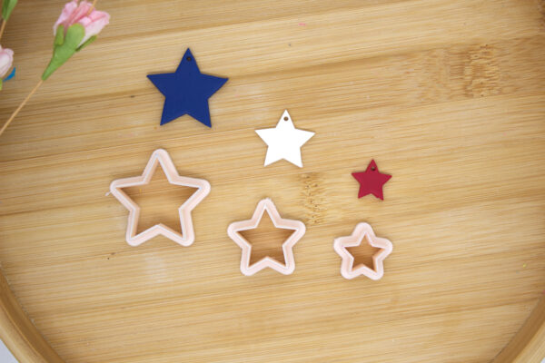 3 polymer clay cutters with a star shape in 3 different sizes, there are also 3 stars made with polymer clay, they have the colors blue, white and red that is trying to show this is a 4th of July theme clay cutters